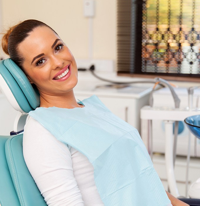 Female dental patient in treatment chair looking to side and smiling