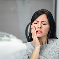 Female dental patient in grey shirt with toothache