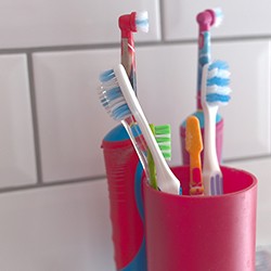 Multiple toothbrushes in red plastic cups